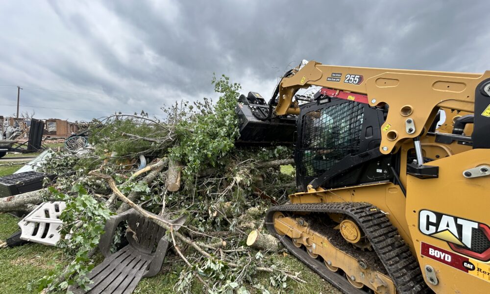 An excavator pulling at fallen branches