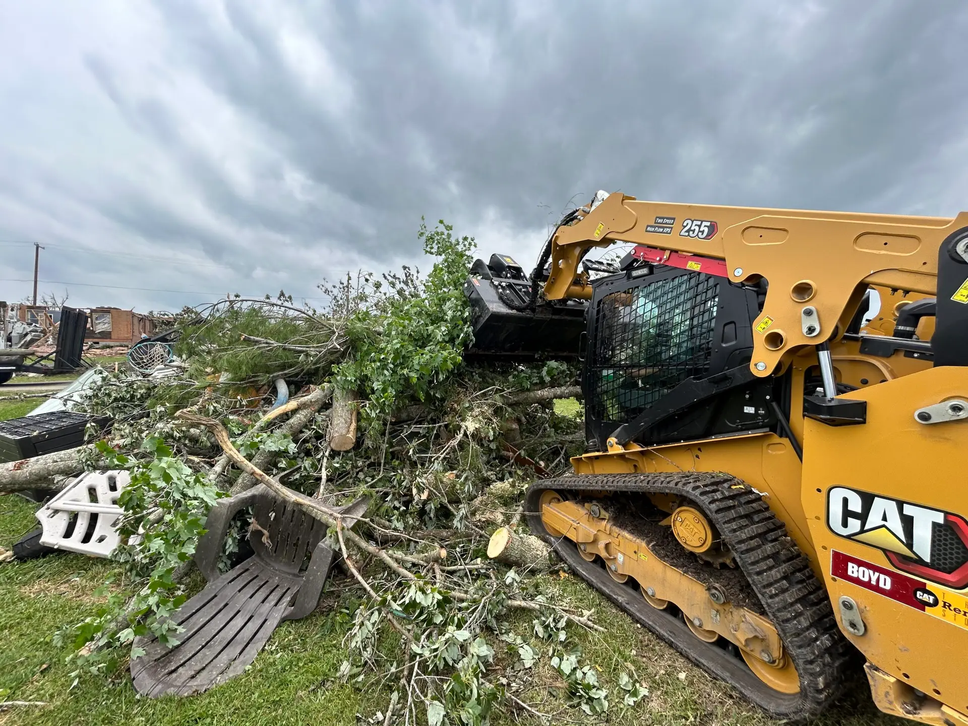 An excavator pulling at fallen branches