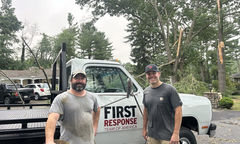 Two men stand in front of a white pickup truck