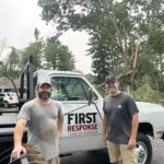 Two men stand in front of a white pickup truck