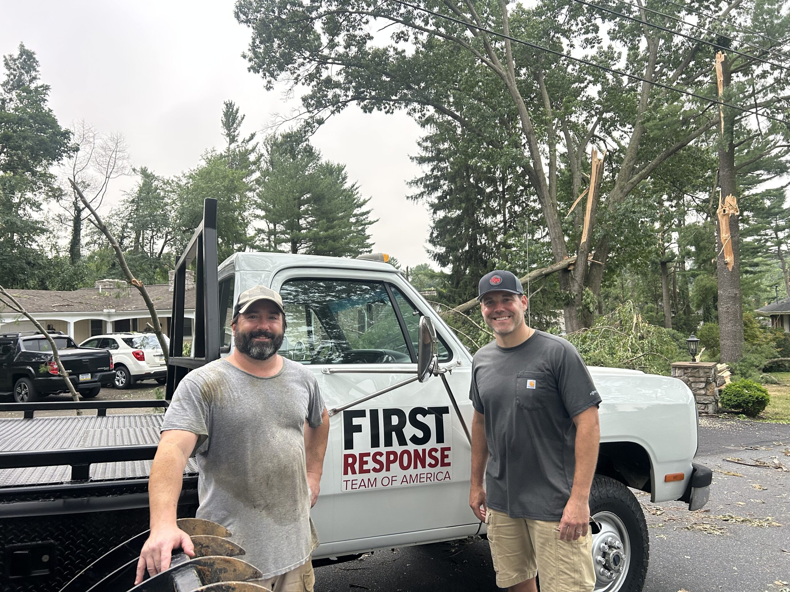 Two men stand in front of a white pickup truck