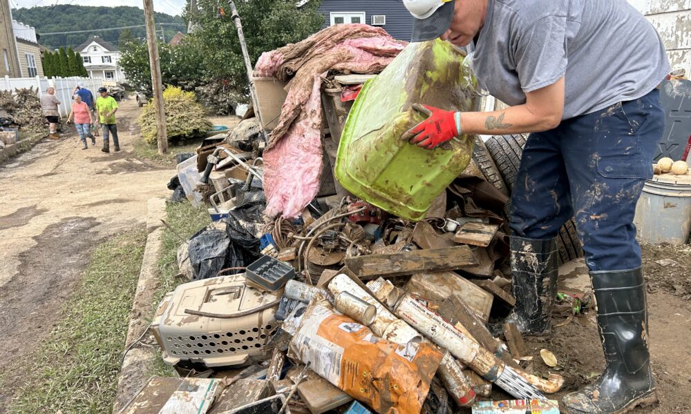 A man emptying a green bin onto a pile of debris