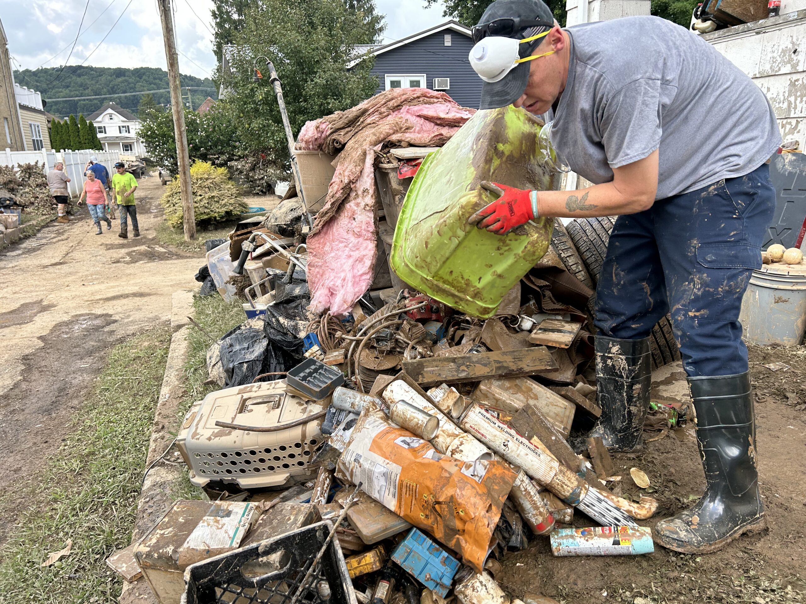 A man emptying a green bin onto a pile of debris