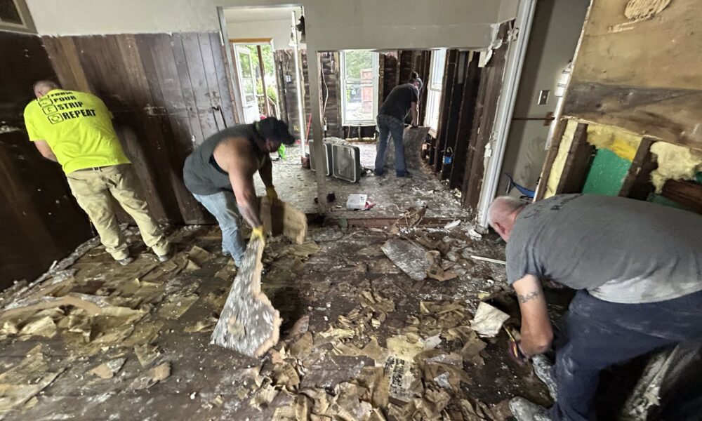 Four people cleaning debris inside a home