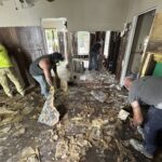 Four people cleaning debris inside a home