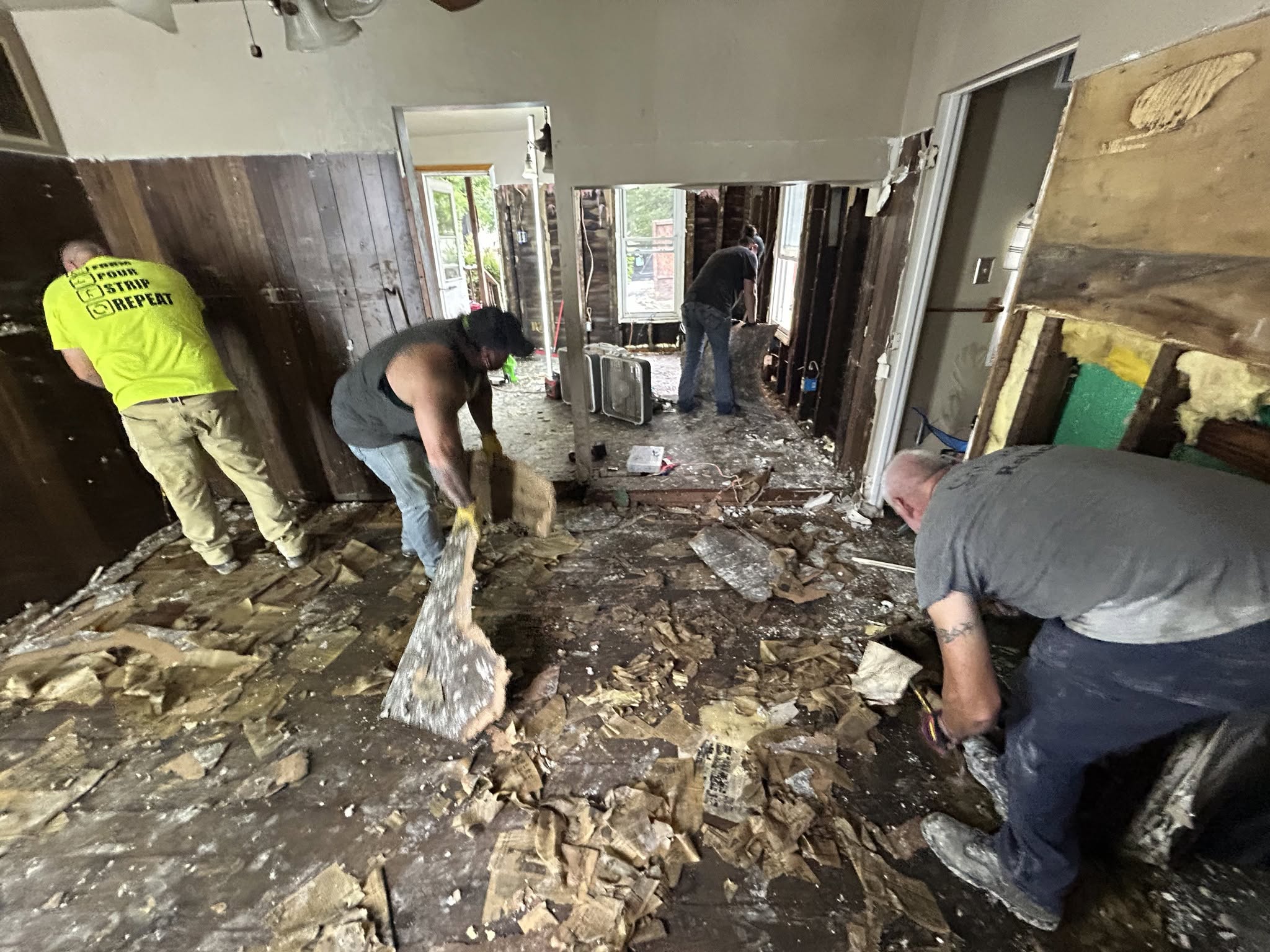 Four people cleaning debris inside a home